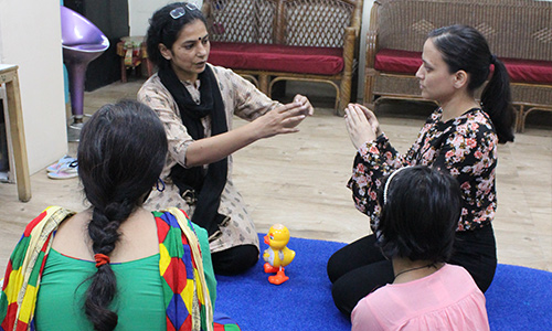 Paediatric occupational therapist conducting a sensory integration activity with an autistic child in a therapy room in India
